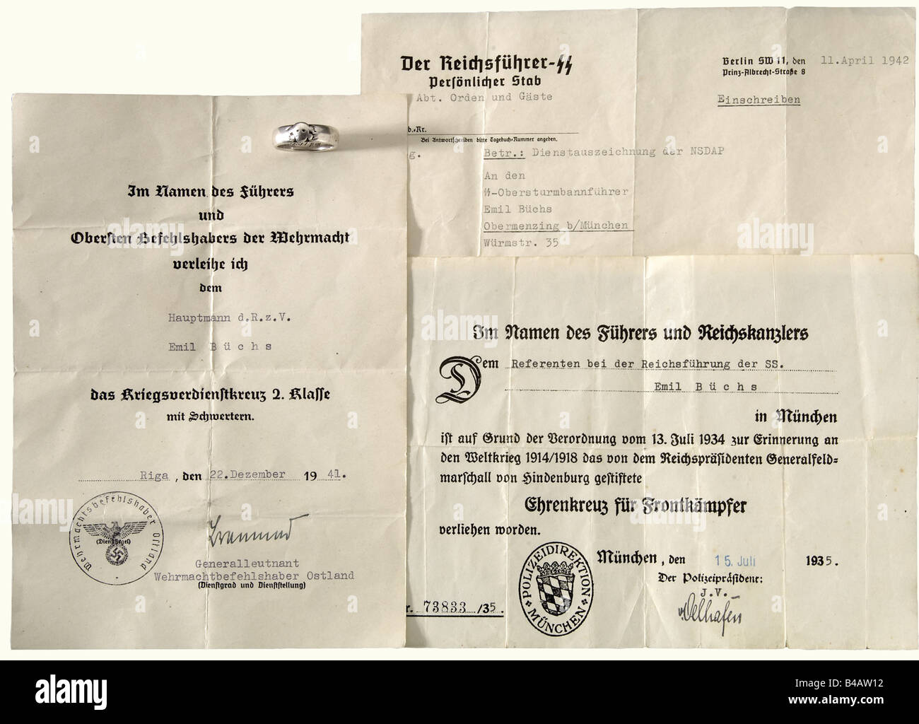 SS-Obersturmbannführer Emil-Büchs - SS-Totenkopfring, und drei Dokumente. Der Ring ist glatt getragen, mit identifizierbarem überlagerten Kopf Des Todes und der gravierten Widmungsbeschriftung S.lb. Büchs 30.6.34 H. Himmler'. Darin enthalten sind die Auszeichnungsdokumente für das Ehrenkreuz für Frontkämpfer 1935 an die "Referenten bei der Reichssatzung der SS" ('Berater der SS-Führung des Reichs') Und das Kriegsverdienstkreuz 2. Klasse mit Schwertern 1941 mit Unterschrift unter Dem Major General und dem Kommandeur der Wehrmacht im Osten Walter Braemers sowie dem Übermittlungsbrief, Stockfoto