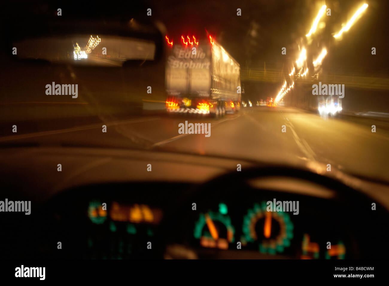 Gesehen durch die Windschutzscheibe, ein Auto fährt mit High-Speed-entlang der Autobahn M1 hinter einer Eddie Stobart-Lastwagen. Stockfoto