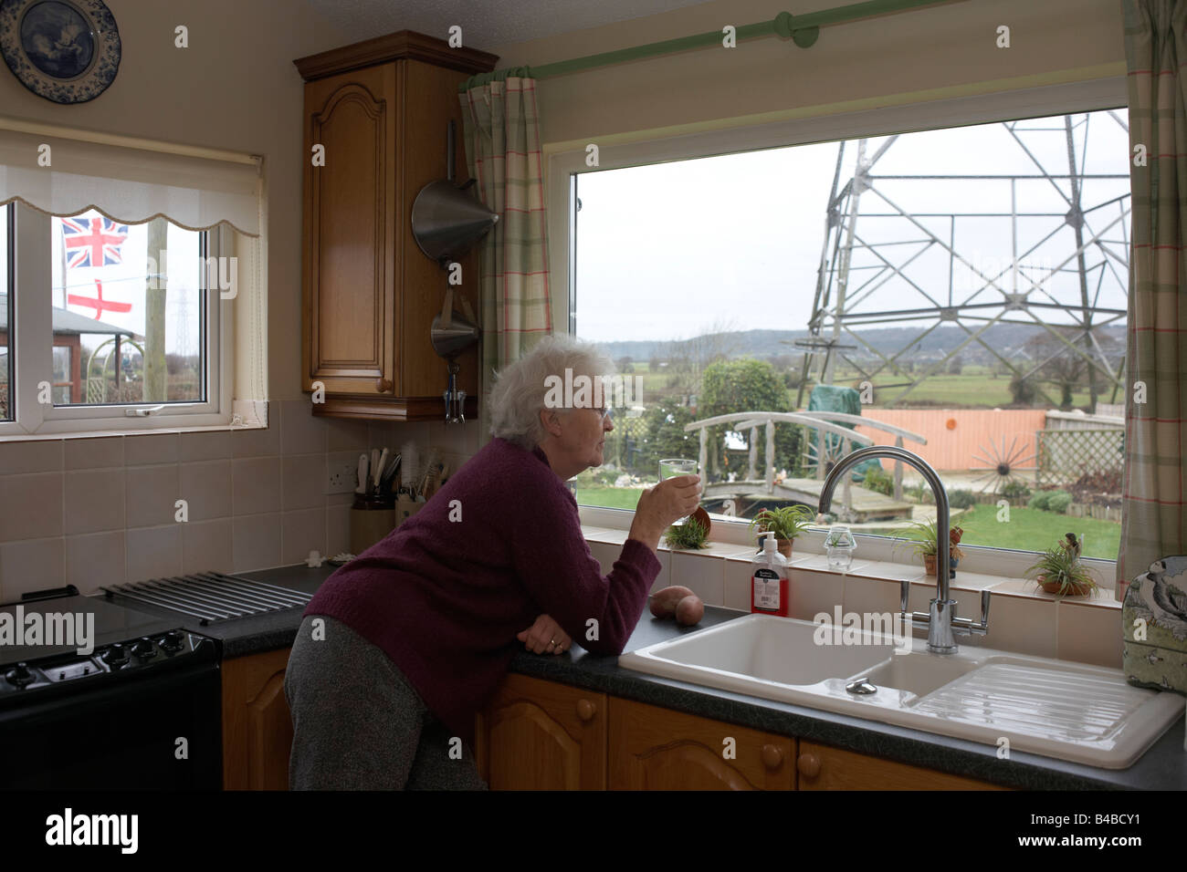 Rentnerin Barbara Dowling Schlucke Tee Ansichten eines Strommastes aus der warmen Küche ihrer Heimat North Somerset Stockfoto