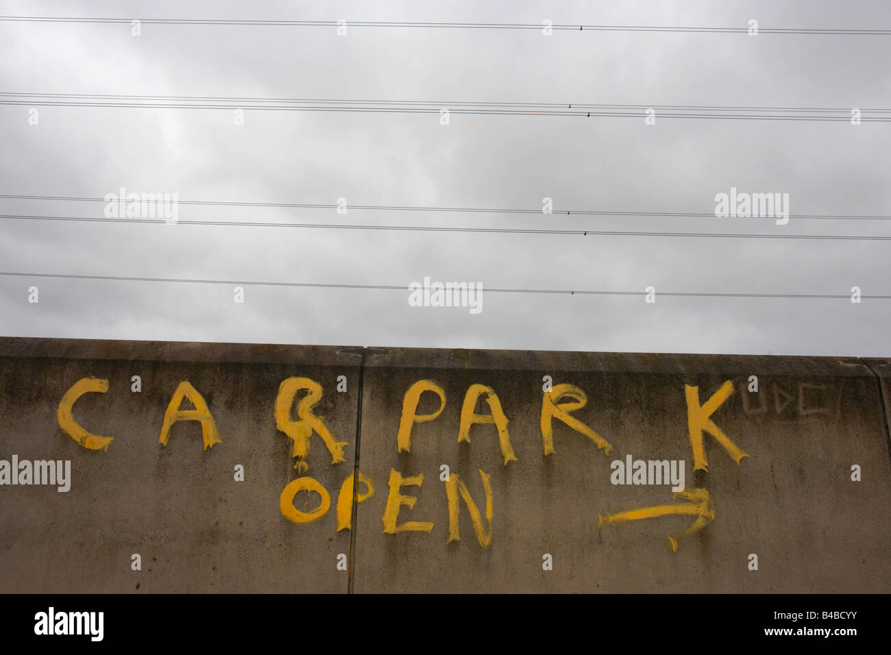 Unter Stromleitungen ist die gelbe Schrift an der Wand, lesen "Parkplatz offen" auf Industriebrachen in East London gemalt. Stockfoto