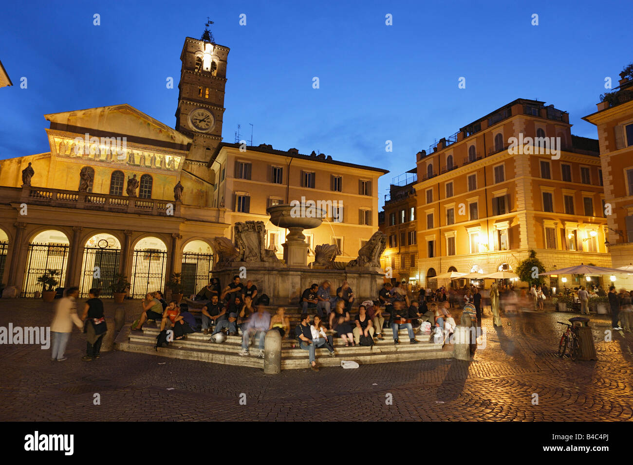 Leute sitzen auf den Stufen eines Brunnens Santa Maria in Trastevere Kirche im Hintergrund Rom Italien Stockfoto