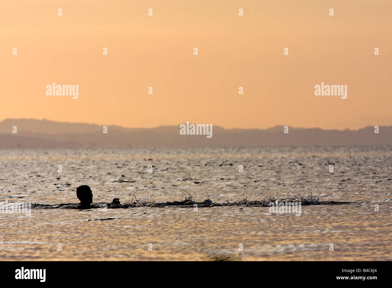 Ein Darlehen Fischer wirft und wirft sein Netz in Nicaragua-See bei Sonnenuntergang in der Silhouette. Stockfoto