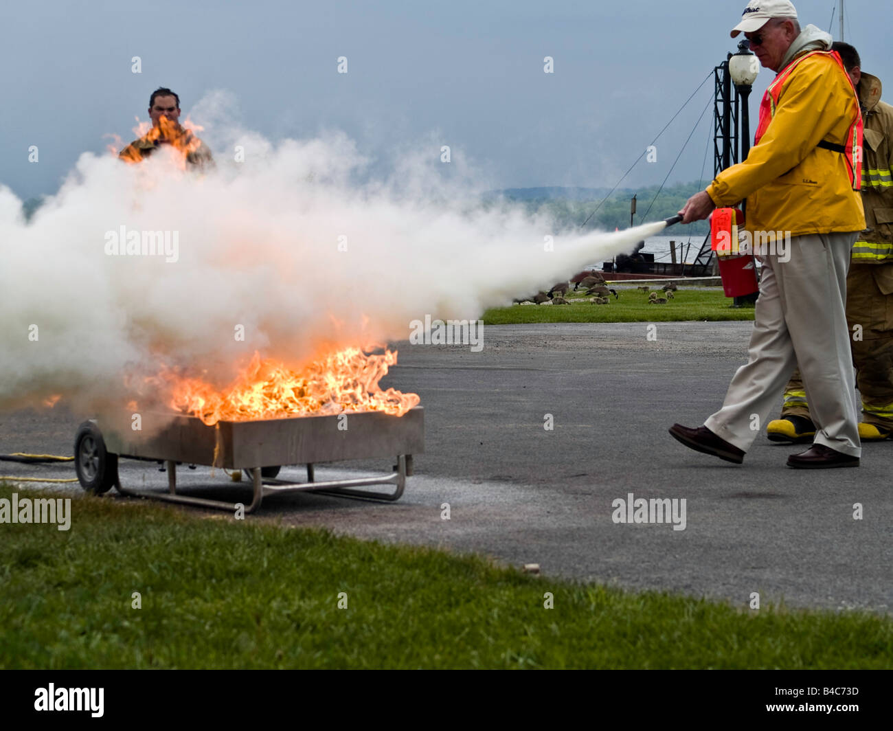 Freiwillige Feuerwehr zeigen Zivilisten, wie man ein Feuer richtig löschen Stockfoto