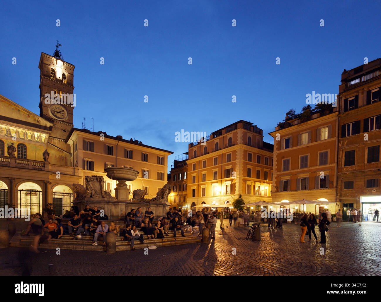 Leute sitzen auf den Stufen eines Brunnens Santa Maria in Trastevere Kirche im Hintergrund Rom Italien Stockfoto