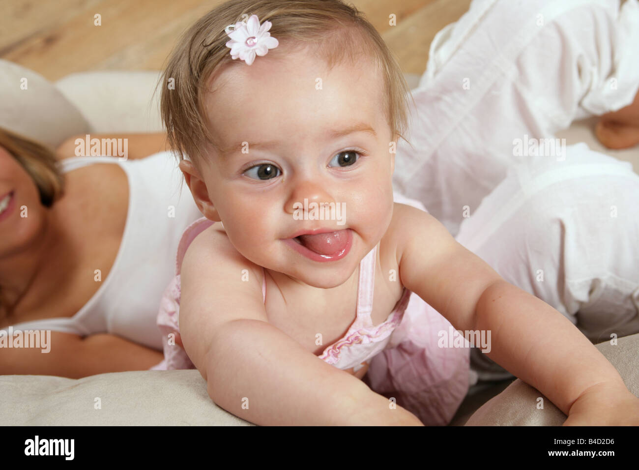 Junge Mutter liegen auf dem Sofa mit ihren neun Monate alten Babymädchen stehend erreichen Sie mit der Zunge, ein Gesicht ziehen Stockfoto