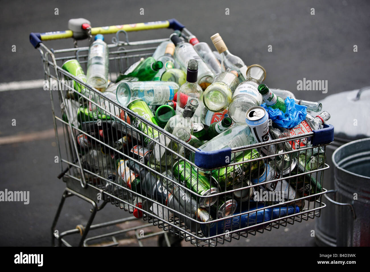 Ein Einkaufswagen voller leere Getränke Flaschen und Dosen auf dem Bürgersteig vor einer Wohnung in Birmingham. Stockfoto