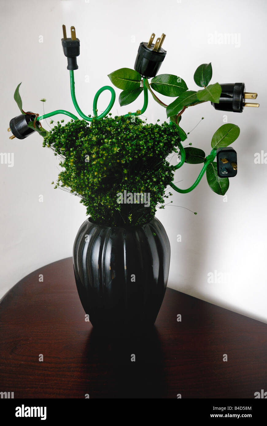 Elektrische Stecker dienen als Blüten in dieser grünen farbigen Blumenarrangement mit einem Ökostrom-Thema in einer vase Stockfoto