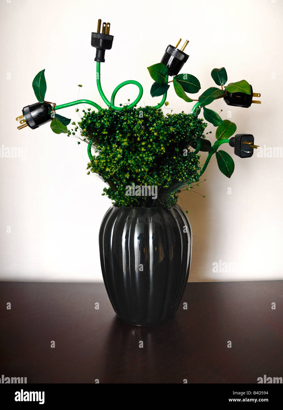 Elektrische Stecker dienen als Blüten in dieser grünen farbigen Blumenarrangement mit einem Ökostrom-Thema in einer vase Stockfoto
