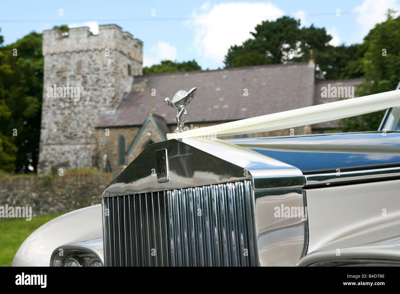 Nahaufnahme von Chrom Frontgrill und fliegenden geflügelte Dame Emblem der weiße Hochzeitsauto rolls Royce mit Kirche im Hintergrund Hochzeit Stockfoto