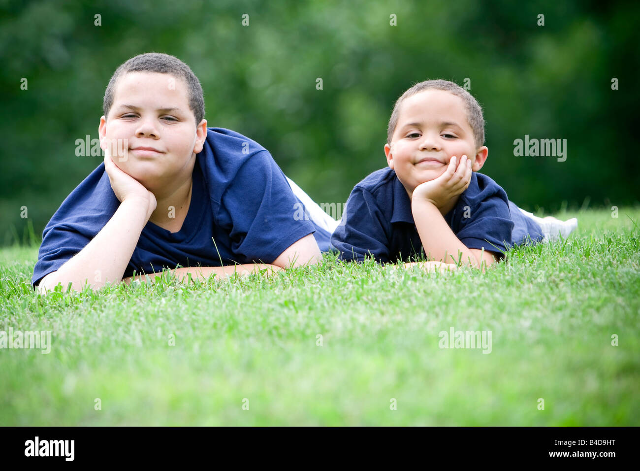 Zwei Brüder, die auf ihre Fronten frischen grünen Gras liegend Stockfoto