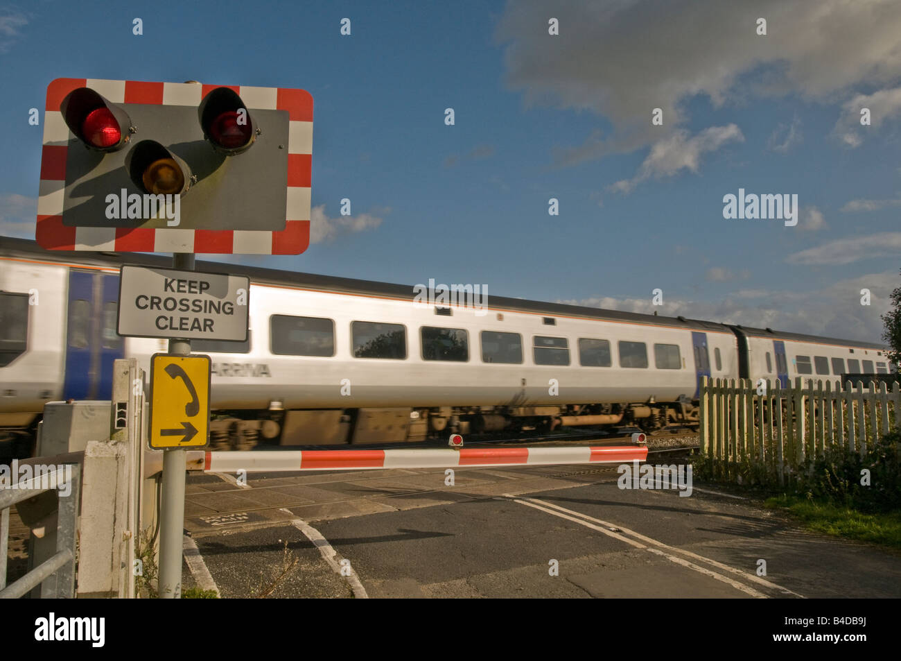 Arriva Personenzug mit Geschwindigkeit aber eine automatisierte Bahnübergang Stockfoto