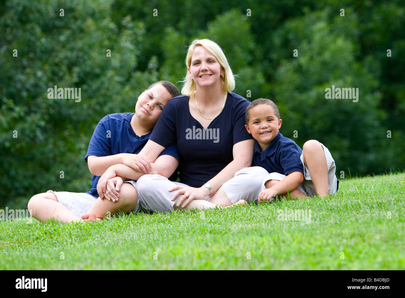 Hübsche Mutter mit ihren beiden Söhnen draußen auf dem Rasen Stockfoto