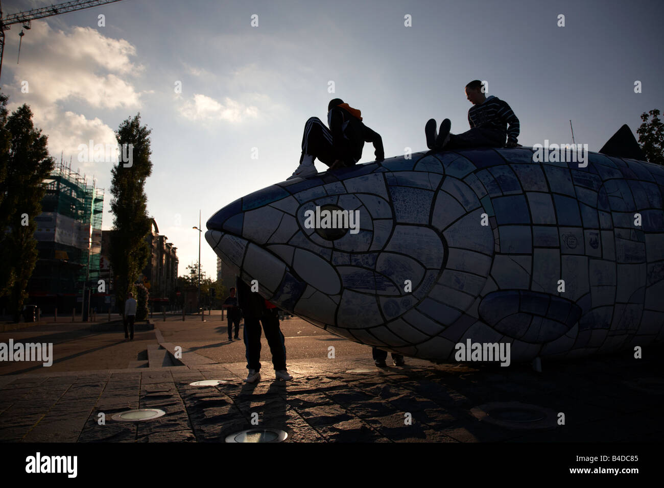 Kinder spielen auf den großen Fisch Lachs Skulptur von John Freundlichkeit neben dem Fluss Lagan in Belfast City Centre Stockfoto