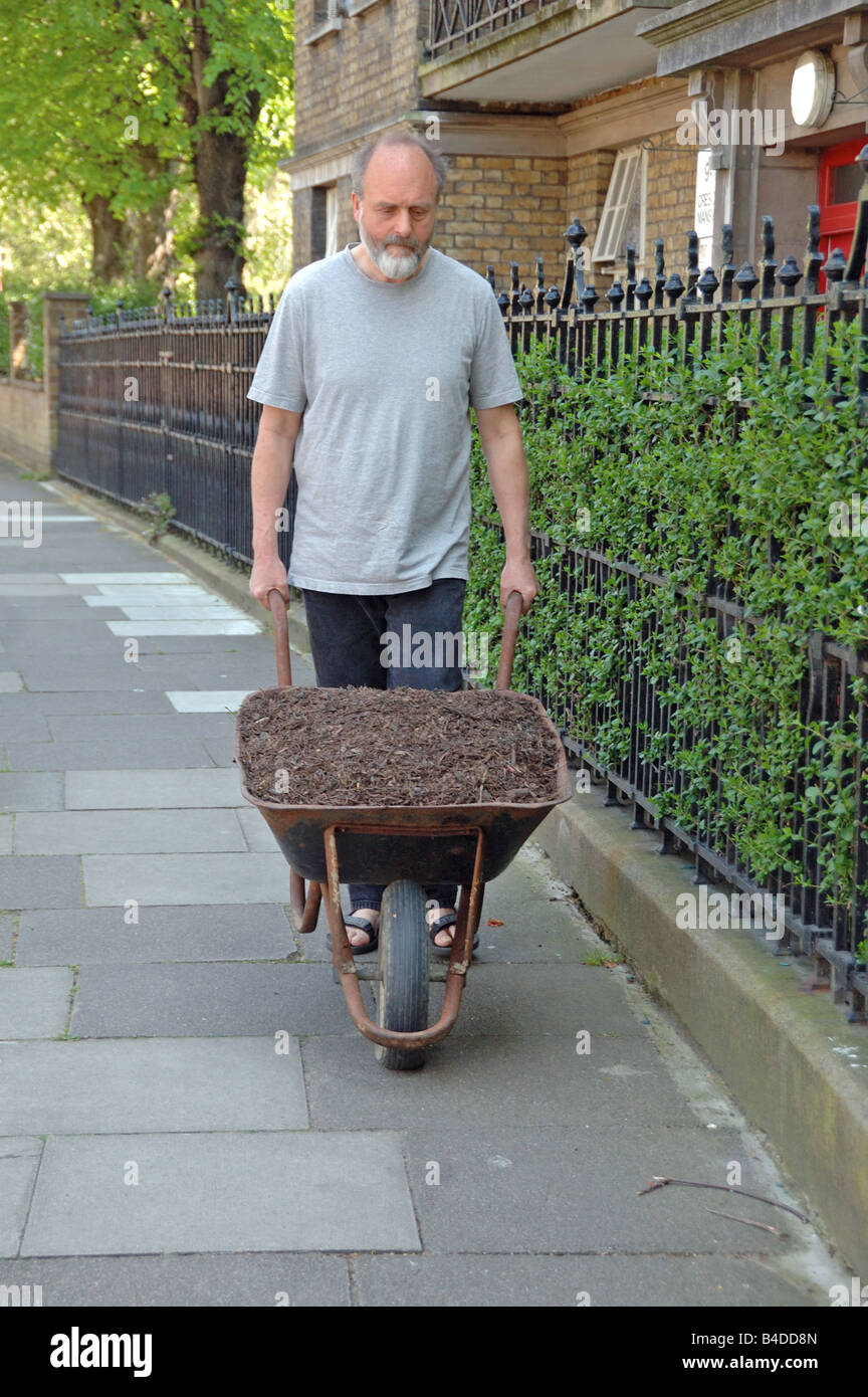 Mann, die Machenschaften Barrow von Kompost entlang Pflaster Highbury London England UK Stockfoto