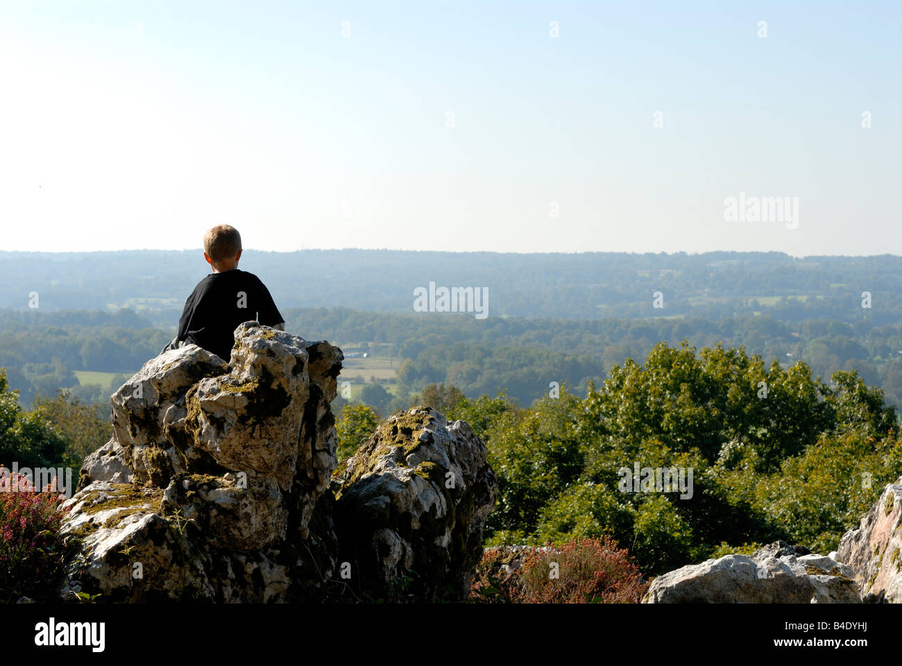 Stock Foto eines jungen Mannes saß allein auf einem Felsvorsprung mit Blick auf eine herrliche Aussicht Stockfoto