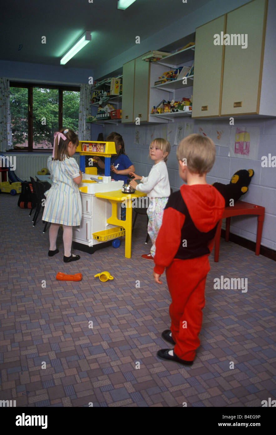 schüchterner junge beobachten andere Kinder im Kindergarten spielen Stockfoto