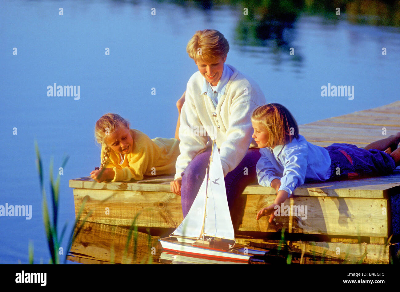 Mutter und Kinder am dock mit dem Spielzeug Segelboot Alter 4 bis 8 Jahren 30 bis 40 5 6 7 35 Stockfoto