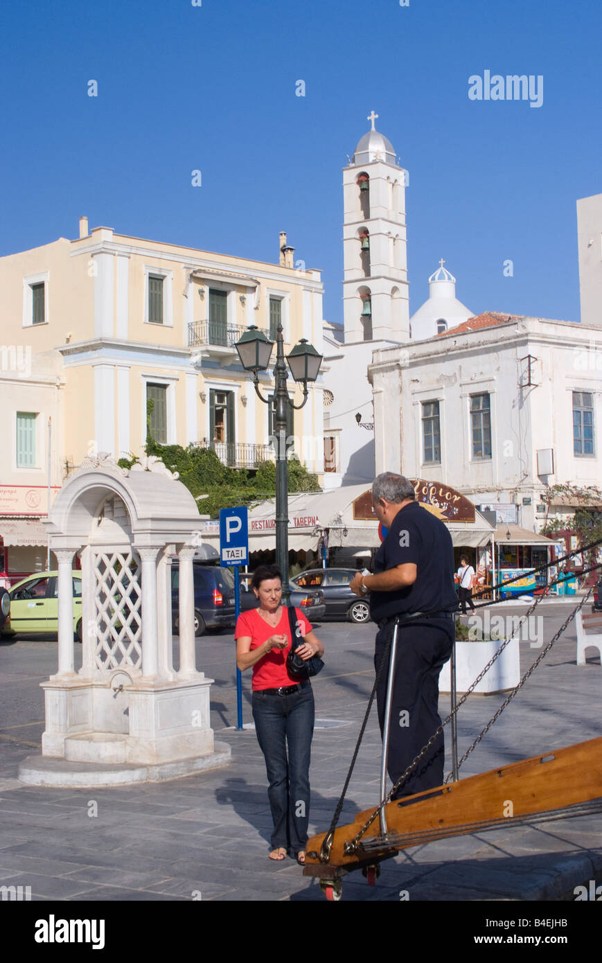 Weibliche Touristen und Crew-Mitglied auf Waterfront mit Brunnen und Kirche in Tinos Stadt Kykladen Ägäis Griechenland Stockfoto