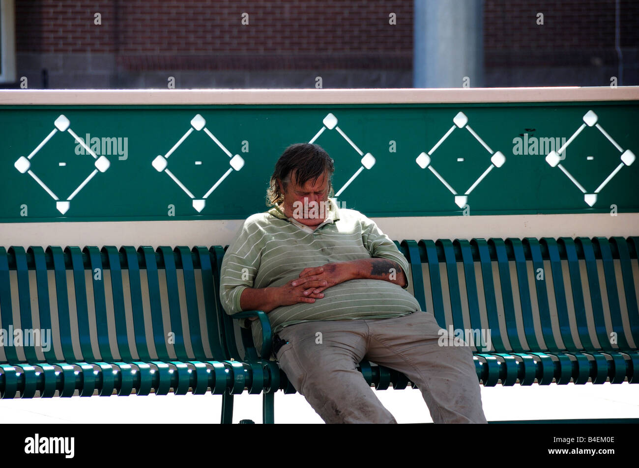 Ein obdachloser Mann schläft auf einer Bank in der noontime Sonne in Oklahoma City, Oklahoma, USA. Stockfoto