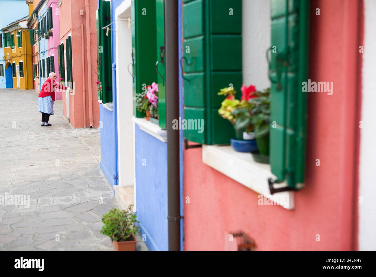 Reife Frau vor ihrem Haus in einer bunten Straße am Burano Insel Venedig Italien Stockfoto