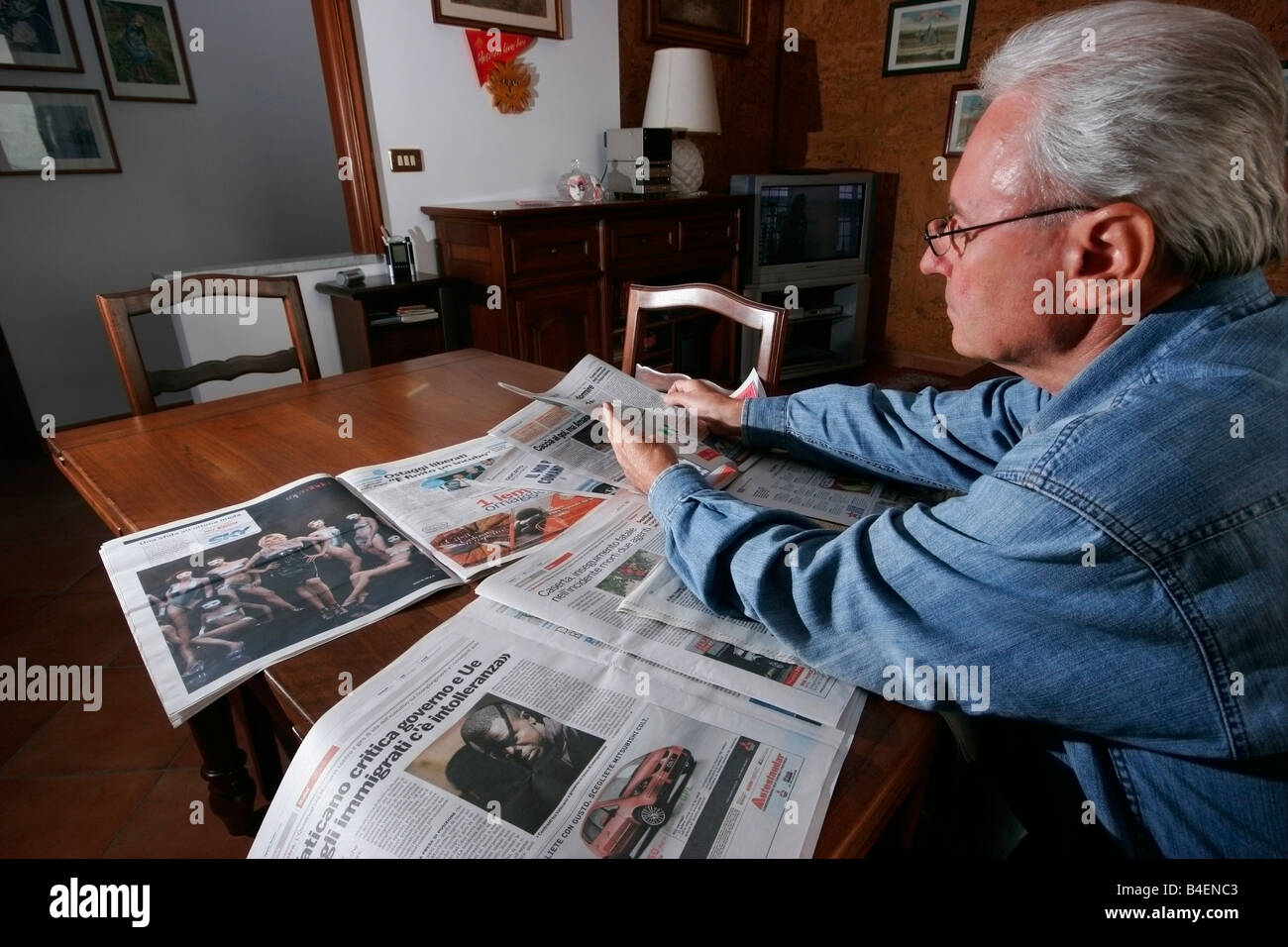 Pensionierter Mann liest einige Zeitungen zu Hause. Stockfoto