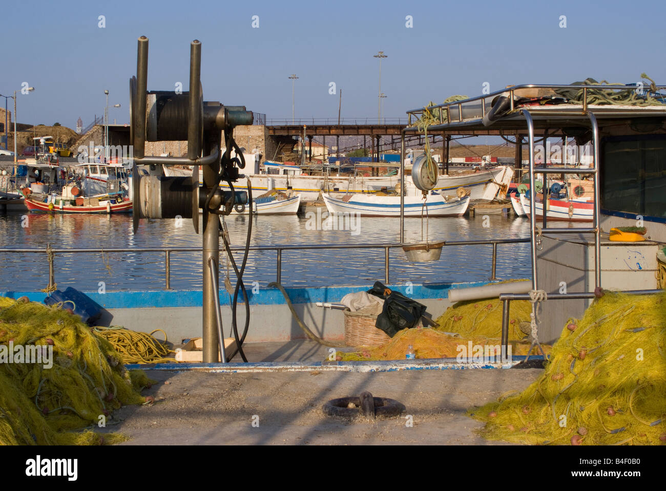Gelbe Fischernetzen und Winde Hebezeuge mit Küstenfischerei Boote festgemacht in Lavrion Hafen griechische Festland Ägäis Griechenland Stockfoto