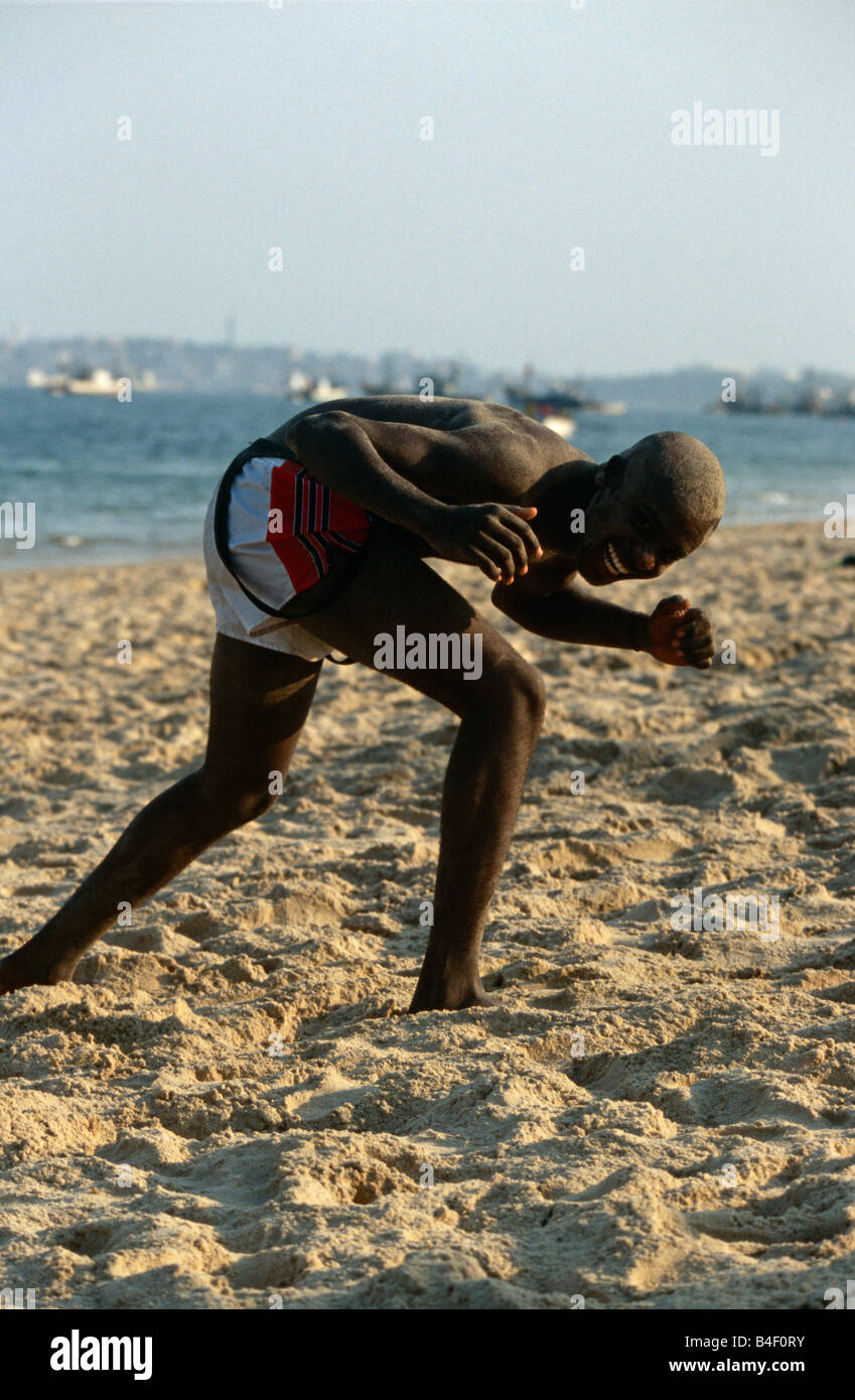 Mann beugte sich über in Aufregung und Gelächter am Strand, Luanda, Angola Stockfoto