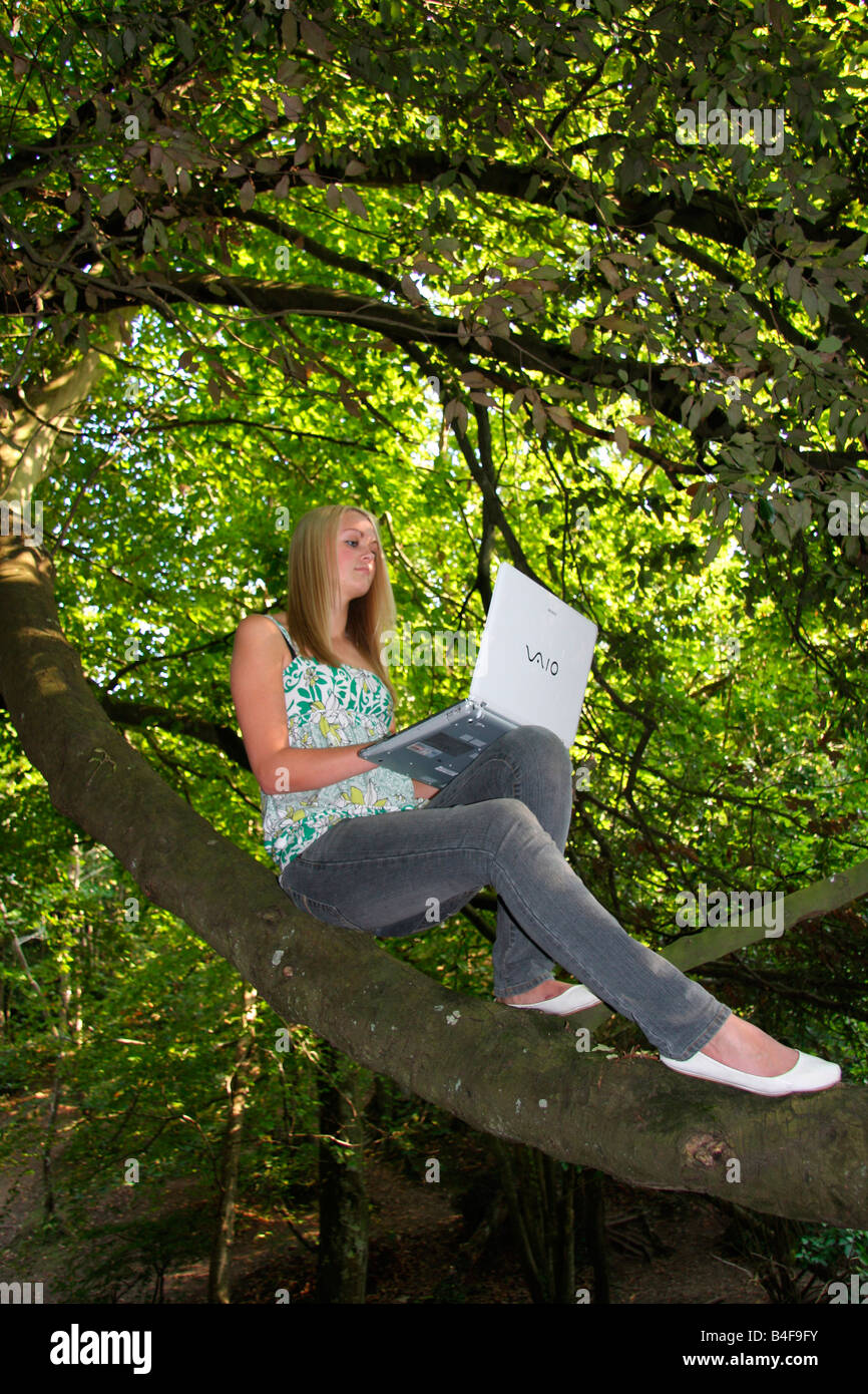 Mädchen mit Laptop in einem Baum Stockfoto