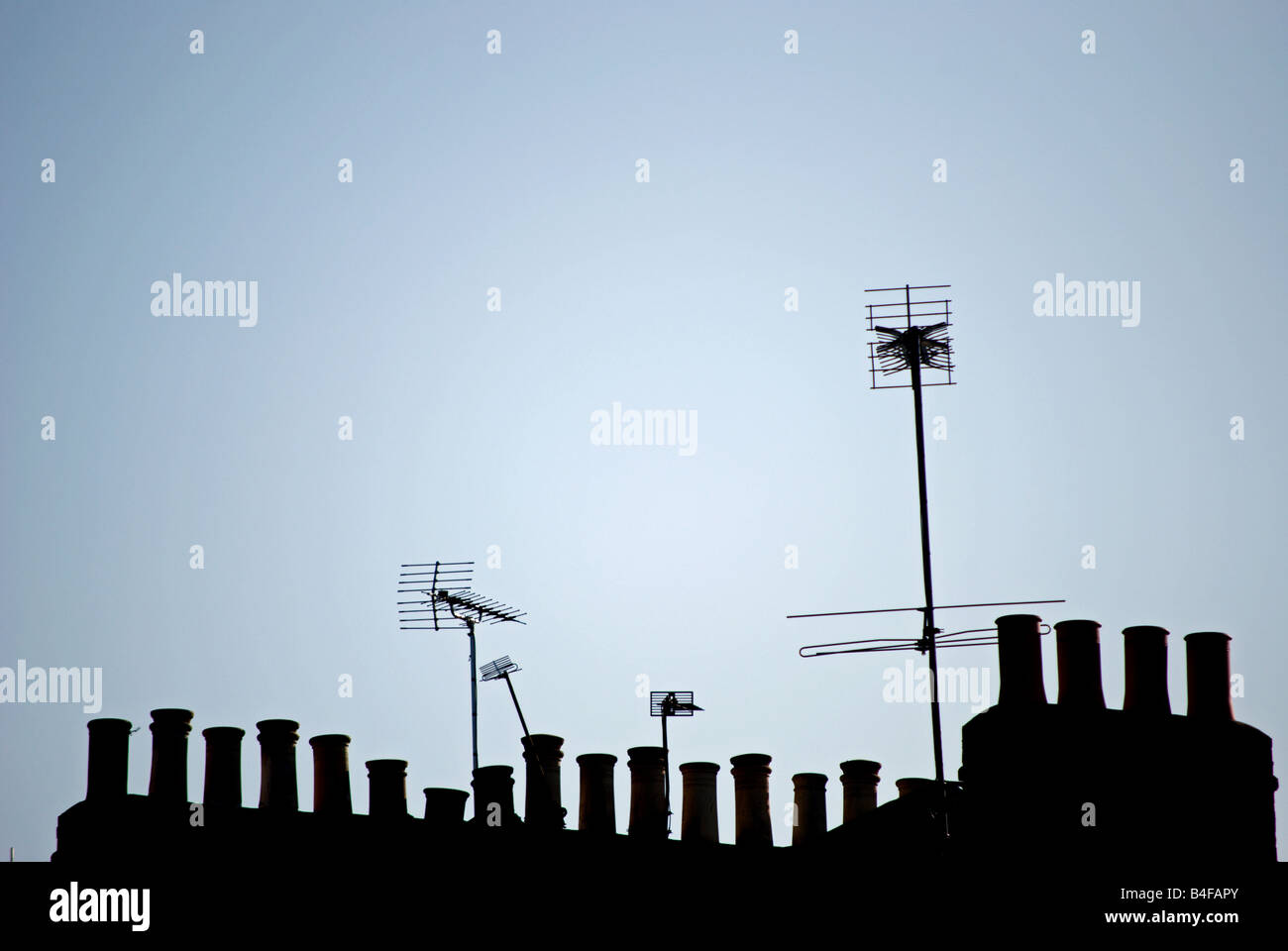 TV-Antennen und Schornstein gesehen in der Silhouette gegen einen frühen blauen Morgenhimmel, in Twickenham, Südwesten von London, england Stockfoto