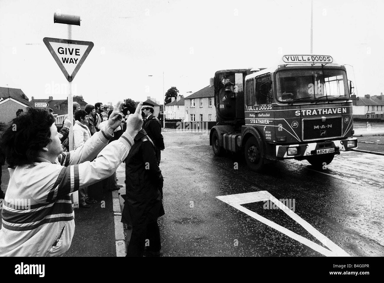 Ein Ravenscraig Kohle Lastwagen vorbei Streikposten während die Bergleute zu schlagen, als Stürmer ihre Finger winken und zeigen das V-Zeichen für Polizeibeamte Mai 1984 Stockfoto