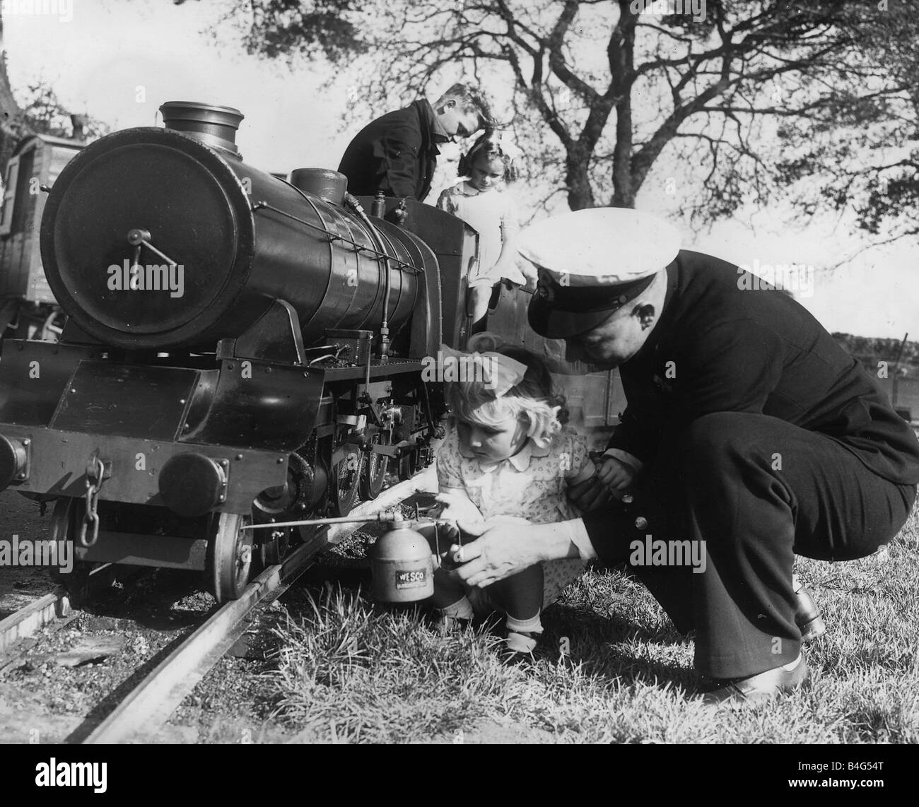 Miniatur Eisenbahn in Privatbesitz, Eisenbahn, die 17-jährige Eric Thurston Neffe des Herstellers Thomas Thurston C P O Mechanist Arnold Rich R N laufen seine kleine Tochter, die Räder der Dampfzug zu Ölen hilft Stockfoto