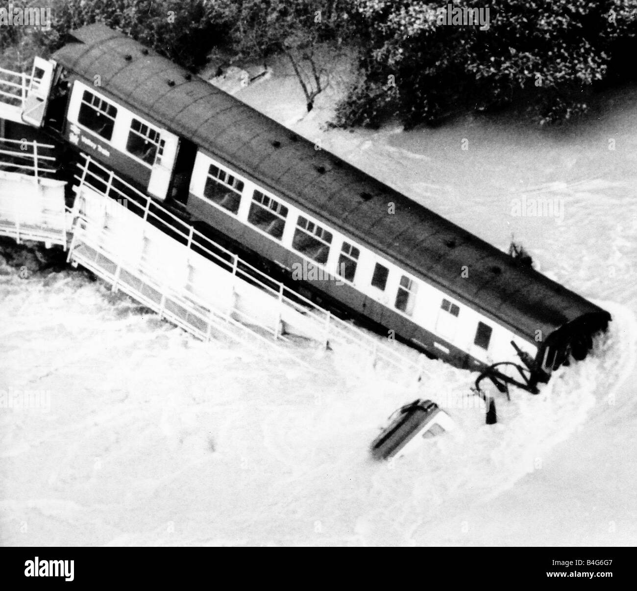 Ein Eisenbahnwagen ist Tauchen Sie ein in die angeschwollenen Fluss Towy während der Blei-Wagen auf der teilweise Einsturz Brücke bleibt Stockfoto