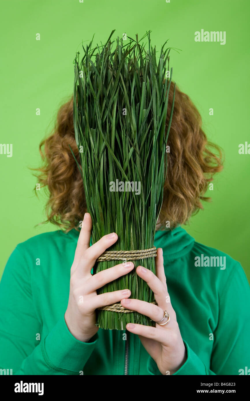 Eine Frau hält eine gebundene Reihe gemähtes Gras vor ihr Gesicht Stockfoto