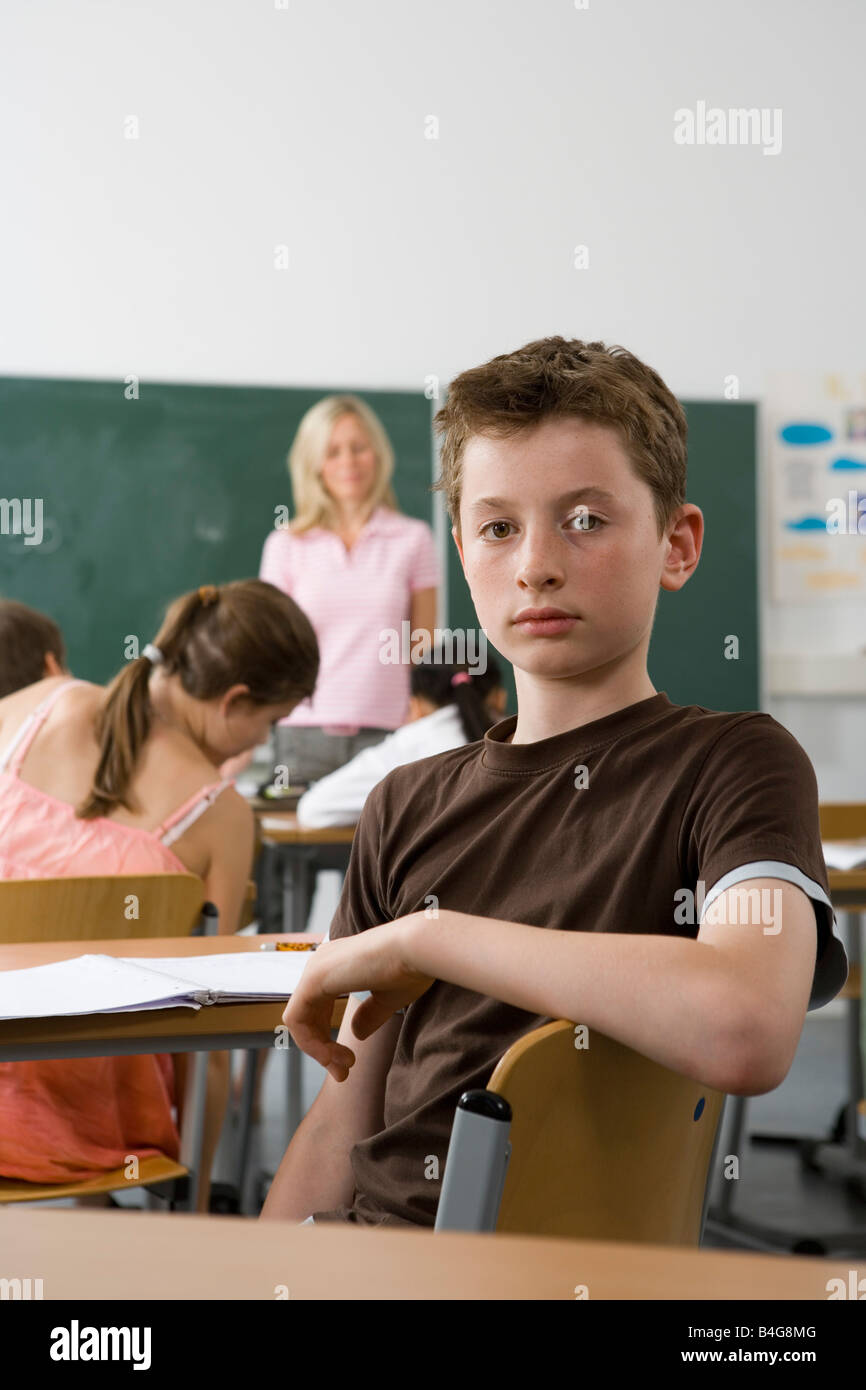 Ein 10-13 junge sitzen im hinteren Teil ein Klassenzimmer, Blick in die Kamera Stockfoto