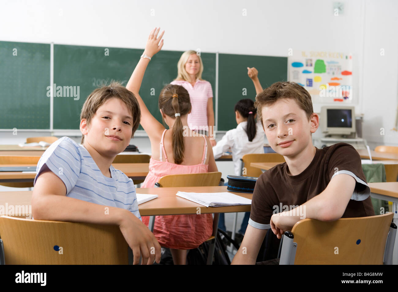 Zwei Pre-heranwachsende Mädchen sitzen im hinteren Teil ein Klassenzimmer, Blick in die Kamera Stockfoto