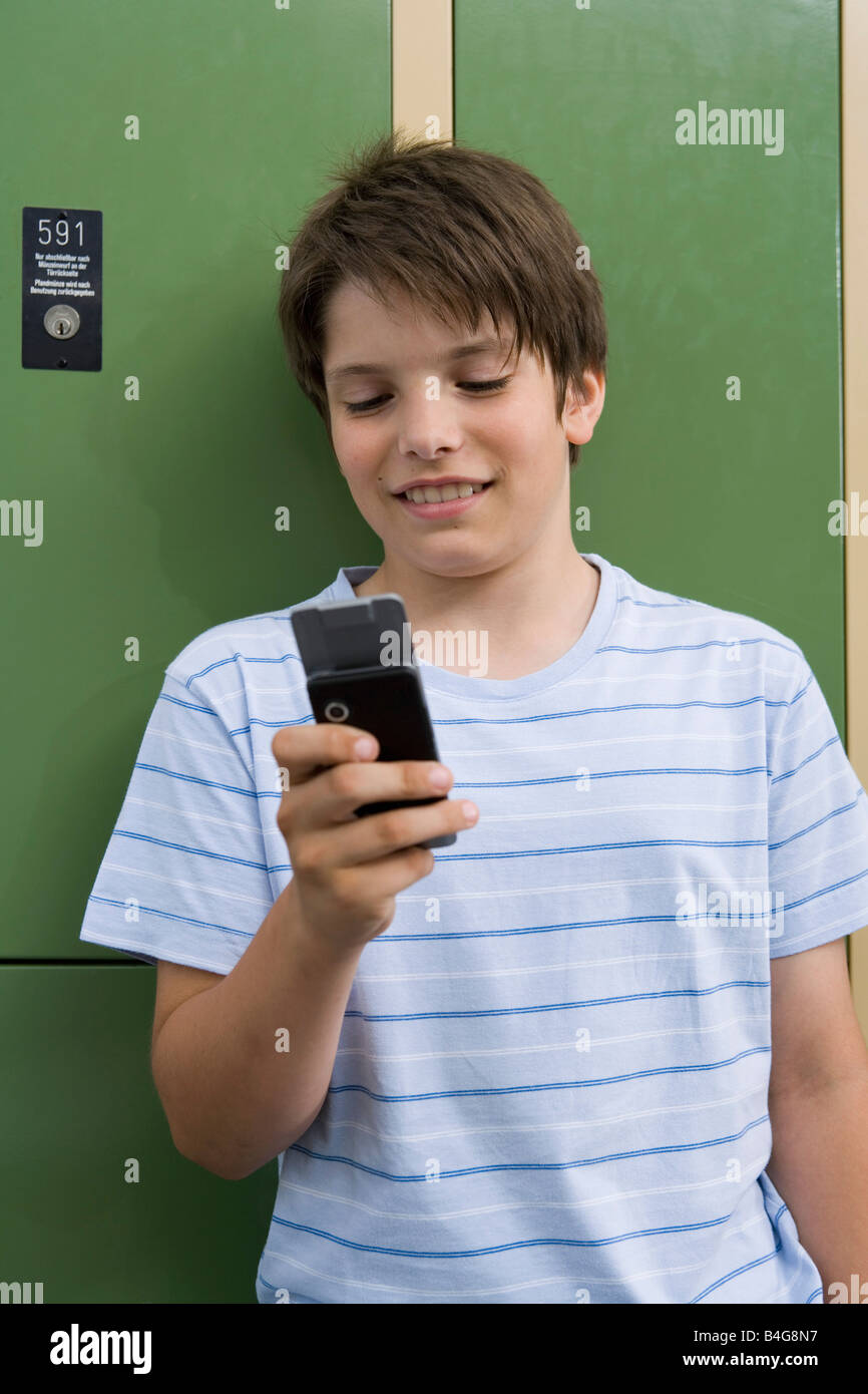 Ein 10-13 junge stützte sich auf Schließfächer Text-messaging Stockfoto
