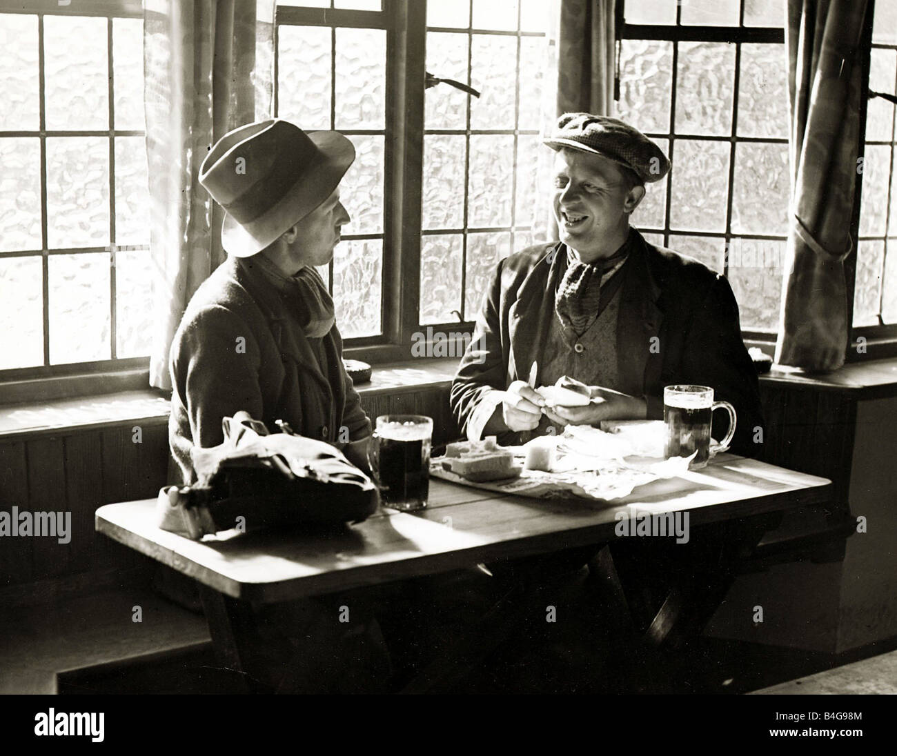 Ein paar Männer, die ihr Mittagessen mit einem Pint Bier in einer Gastwirtschaft Circa 1935 Stockfoto