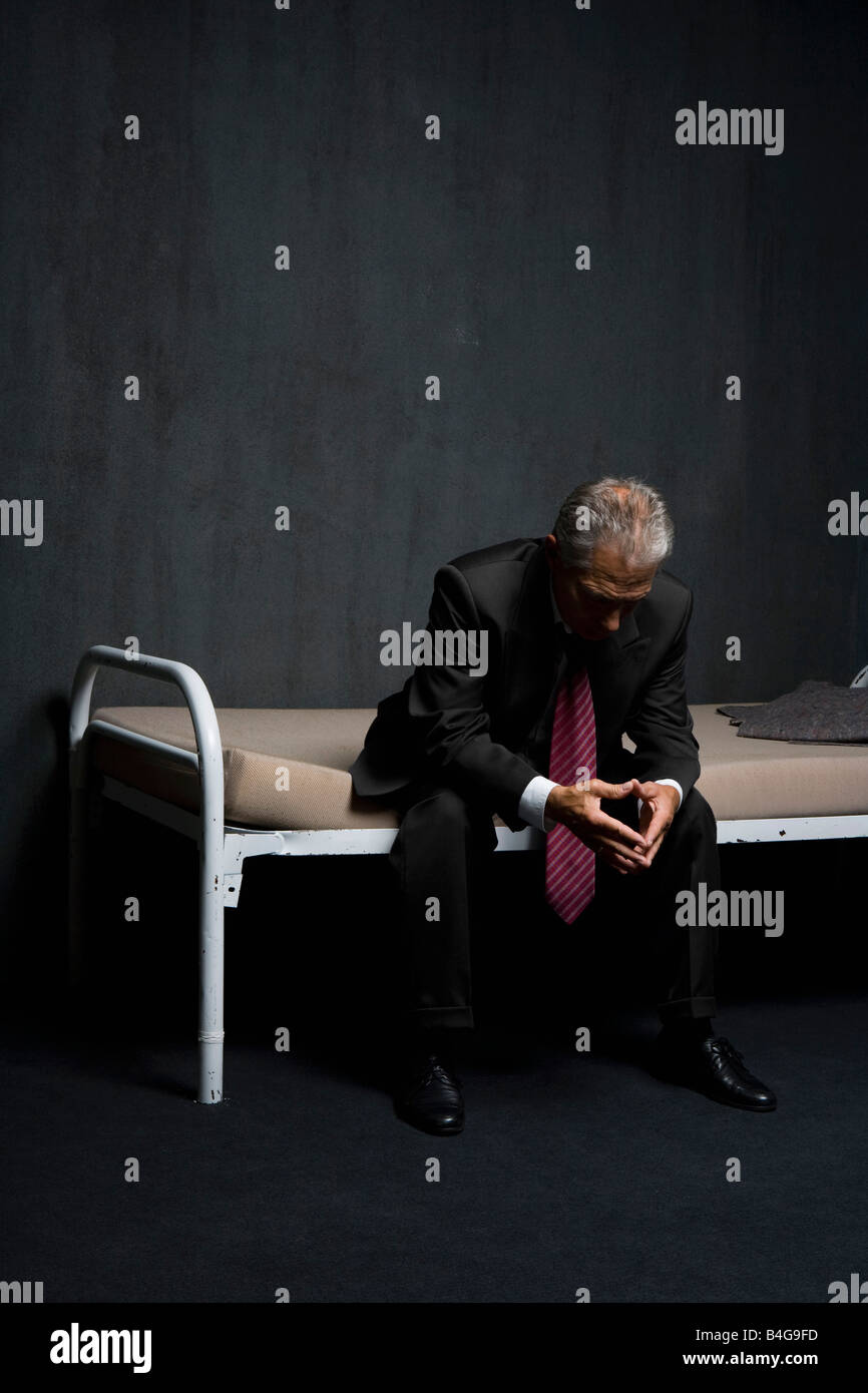 Ein Business-Mann sitzt auf einem Gefängnis-Zelle-Bett Stockfoto