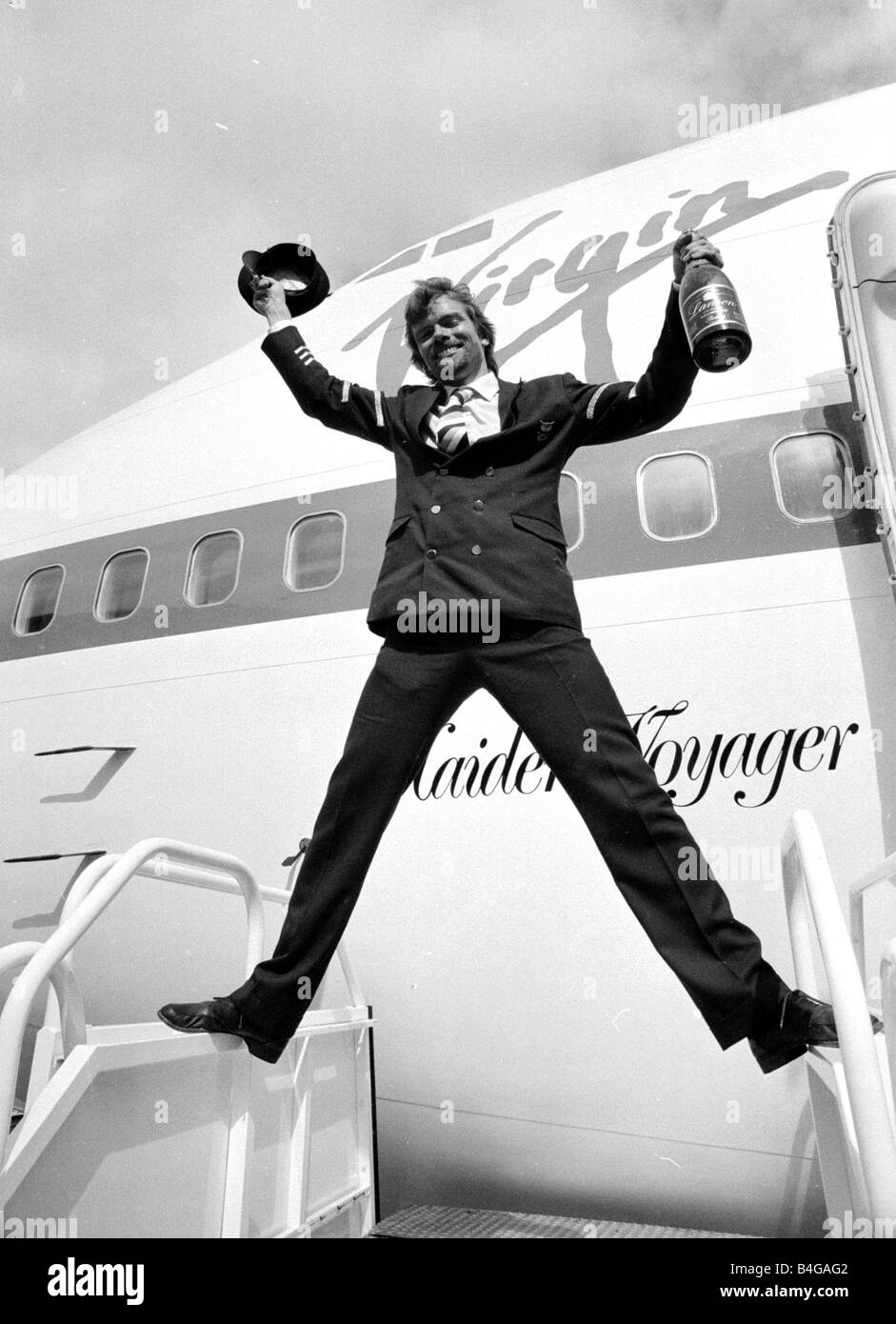 Richard Branson Flasche Champagner und Piloten Hut zu halten, wie er Virgin Atlantic Airlines Erstflug Juni 1984 feiert Stockfoto