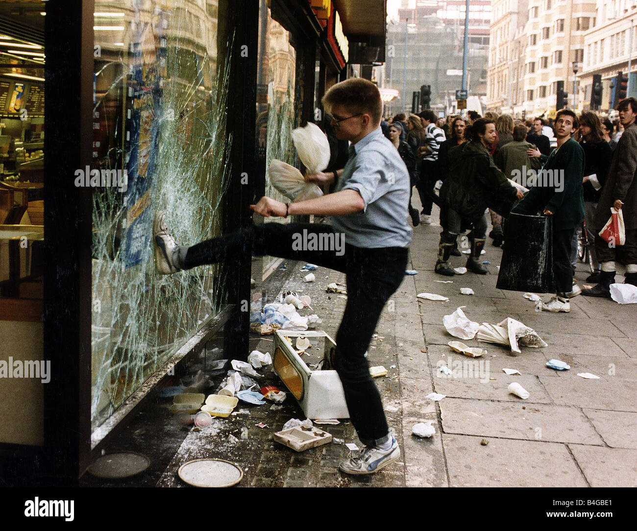 Ein Demonstrant gegen die Kopfsteuer zerschlägt ein Schaufenster auf dem Trafalgar Square März 1990 Stockfoto