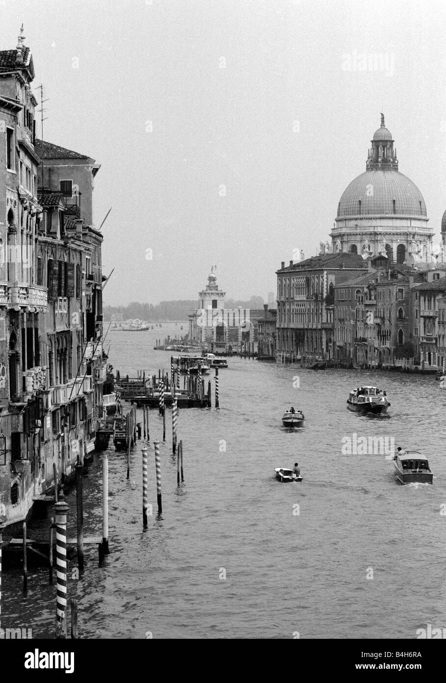 Boote, die ihren Weg entlang einer der wichtigsten Kanäle in Venedig Italien mit der Santa Maria Della Salute Kirche hinter Mai 1987 Stockfoto