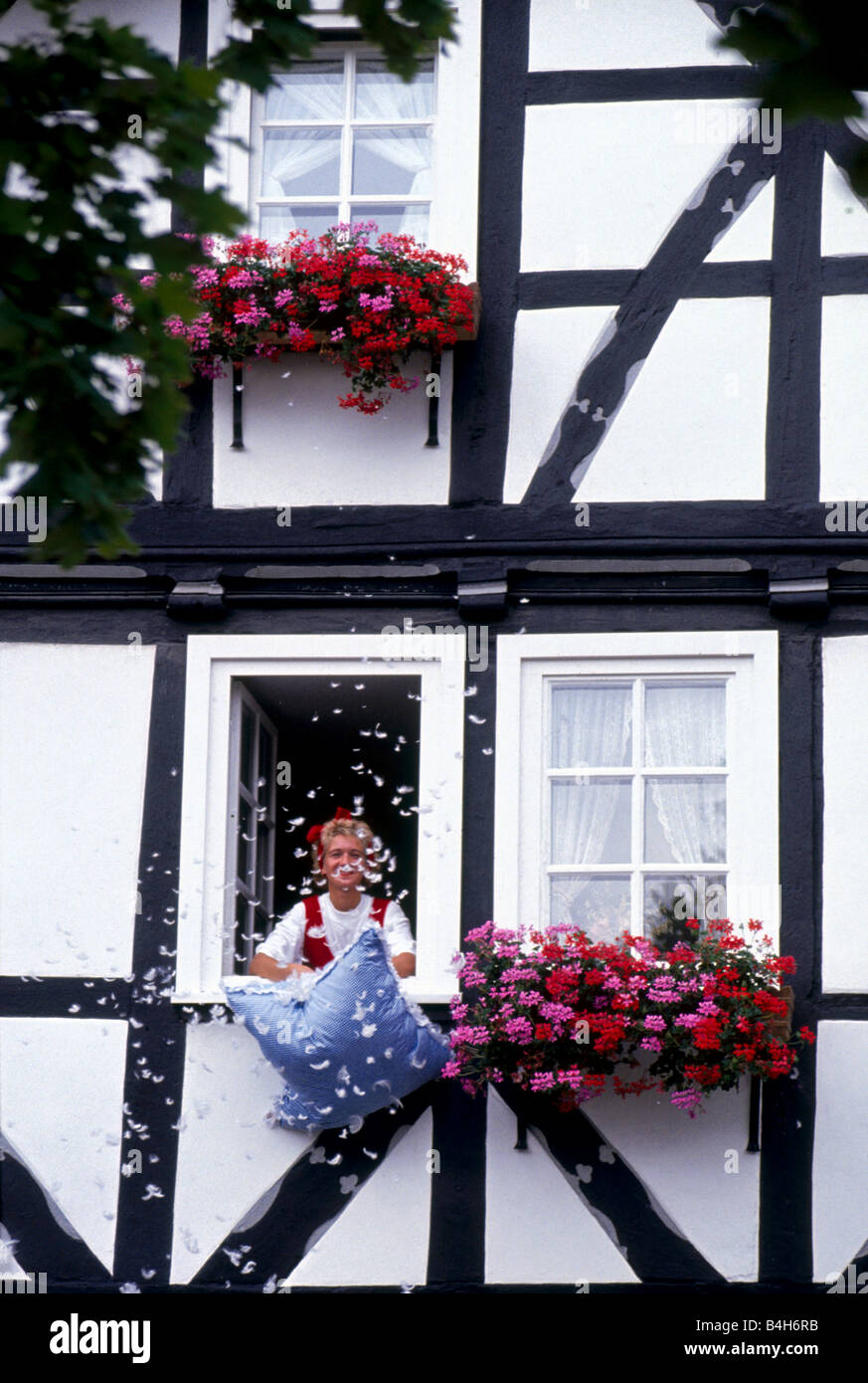 Frau mit Kissen am Fenster des Hauses, Bad Sooden-Allendorf, Deutschland Stockfoto