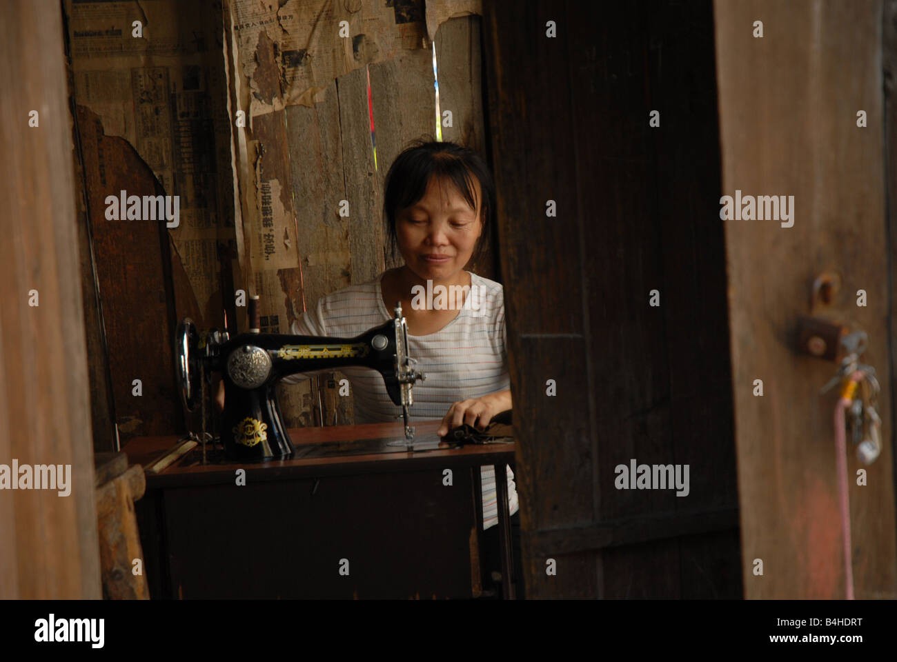 Eine Frau mit ihrer Nähmaschine in Landgemeinde Chongqing, China. Stockfoto