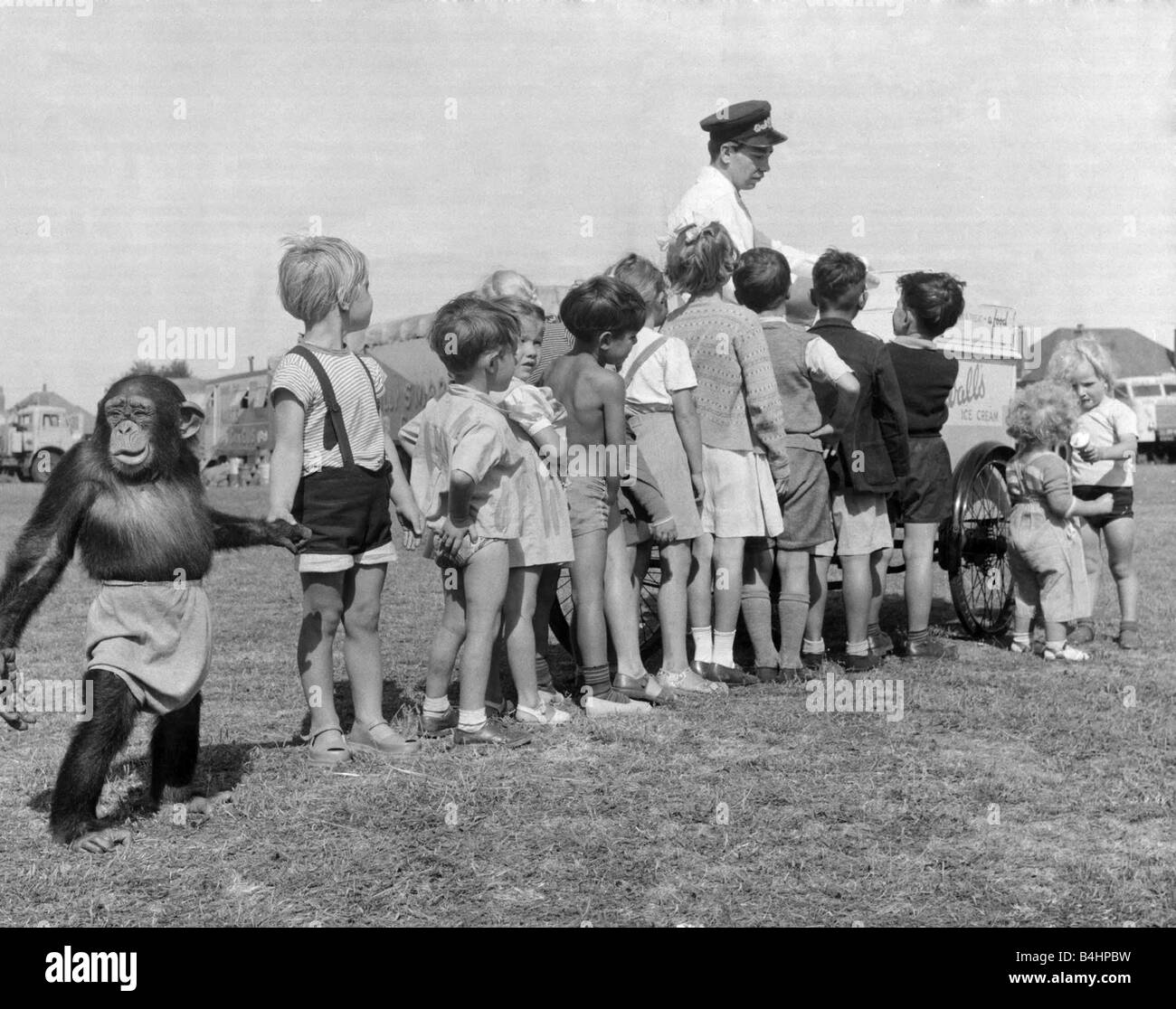 Kinder-Warteschlange mit ihren Schimpansen Freund für ein Eis bei Billy Smart Zirkus Stockfoto