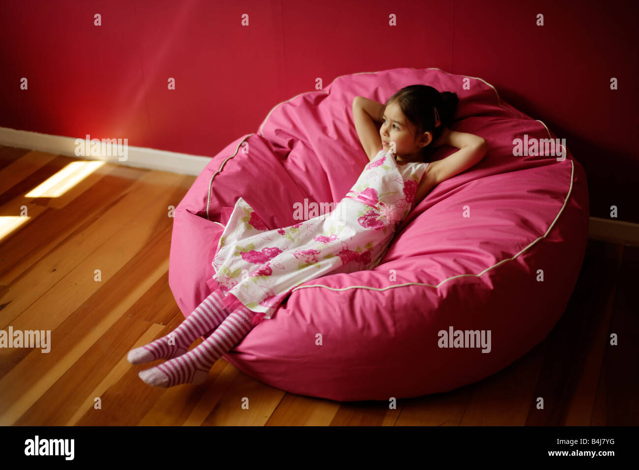 Mädchen 5 entspannt auf rosa Sitzsack Stockfoto