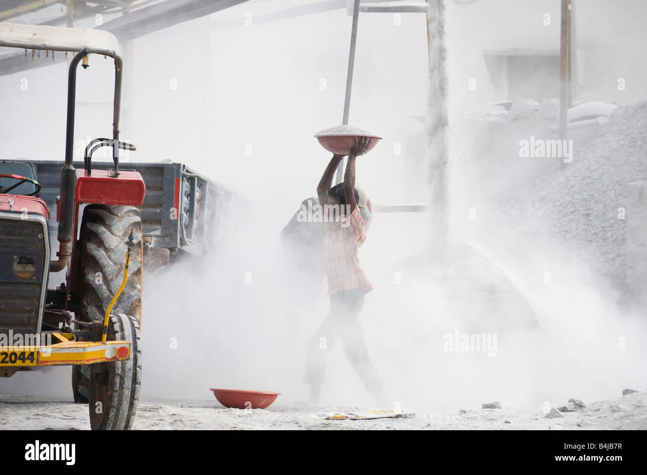 Indische Männer setzen zerdrückten Stein in einen Anhänger, umgeben von Staub, ungeschützt auf einen Stein zerkleinern funktioniert. Andhra Pradesh. Indien Stockfoto