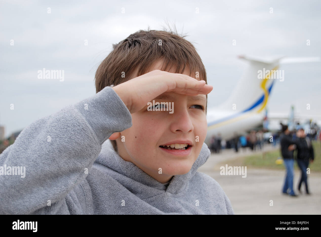 Junge Peerings mit Palm in der Nähe von Stirn gegen Flugzeug, Fokus auf den Vordergrund Stockfoto