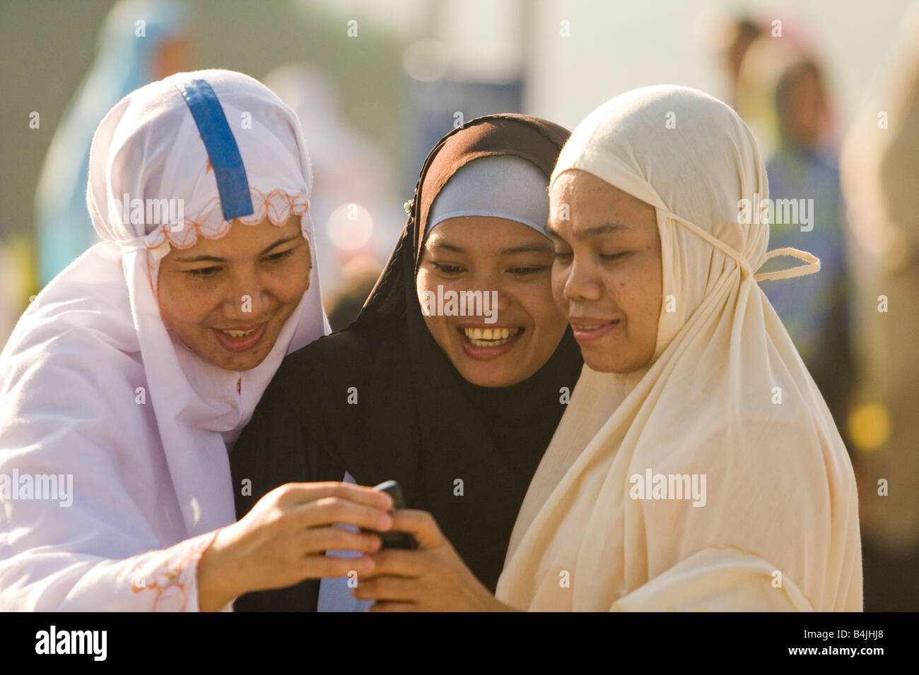 Muslimische Frauen in ihrer Kleidung, Blick auf ein Mobiltelefon Stockfoto