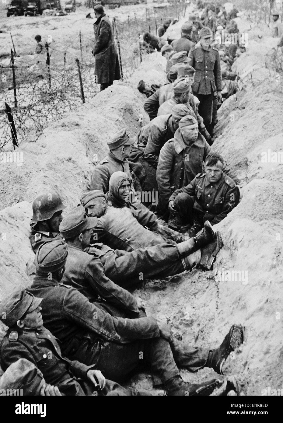 Kampf erschöpfte deutschen Kriegsgefangenen sind in einem eigenen Strand Verteidigung geschützt waren Gräben während des Wartens auf ein Kriegsgefangen Lager in Frankreich sie marschierten unter den ersten, von der Allied Expeditionary Force während der D-Day Landungen in Frankreich WW2 erfasst werden Stockfoto