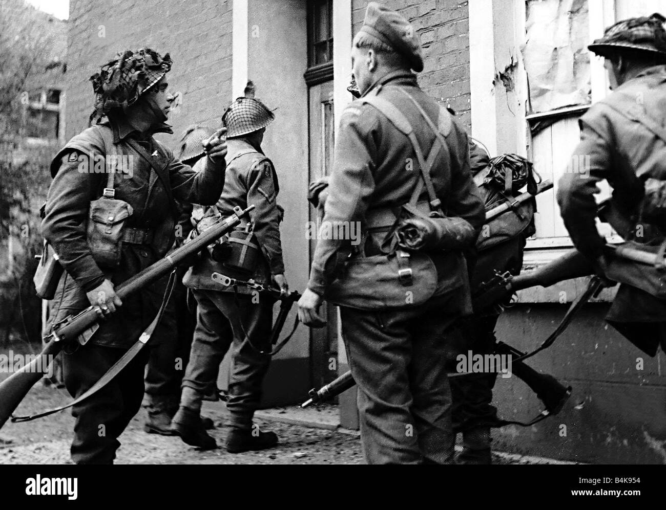 WW2 British Armour stößt in Deutschland April 1945 Infanterie der 7. Panzerdivision Halt vor einem Haus während des Angriffs Stockfoto